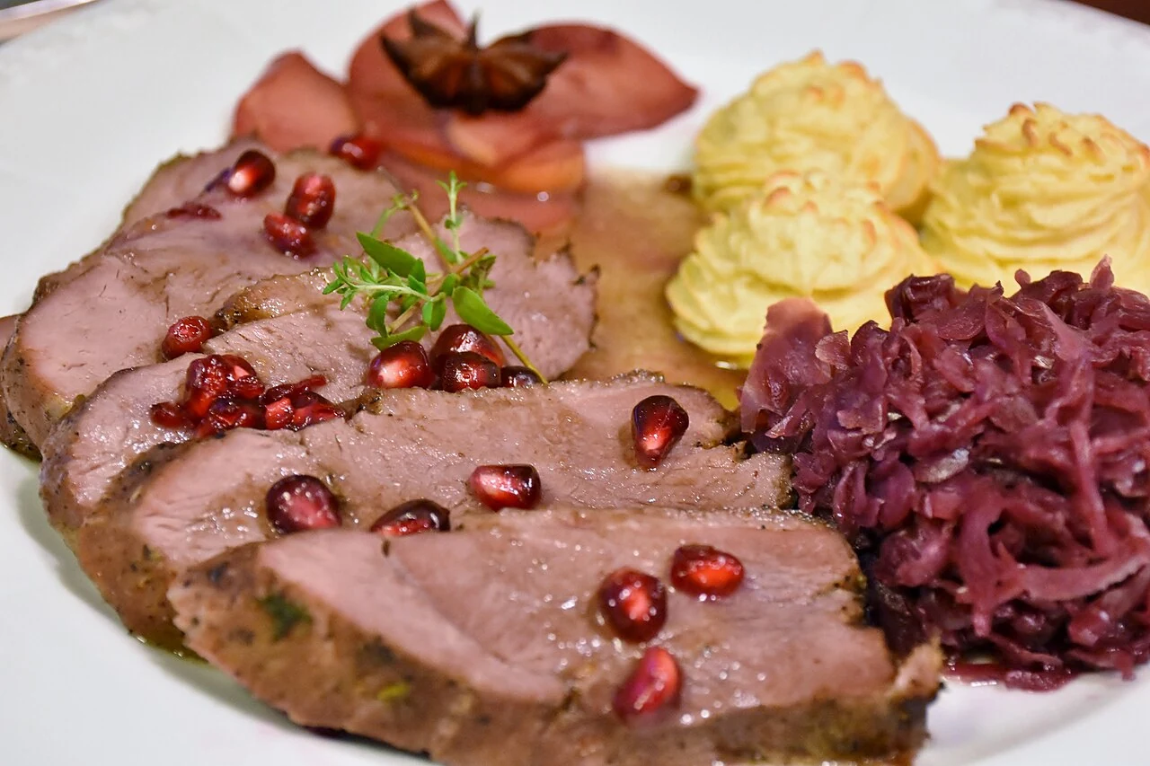 Pečena gos z rdečim zeljem in prilogo na krožniku